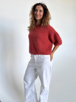 Modelfoto af pige i terracottafarvet Poppy strik t-shirt og hvide Nanna jeans. Alt er fra BySofieSønderby