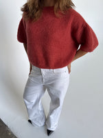 Modelfoto af pige i terracottafarvet Poppy strik t-shirt og hvide Nanna jeans. Alt er fra BySofieSønderby