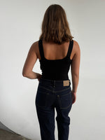Modelfoto af pige som bærer en Posie top i sort, samt et par mørkeblå jeans. Alt fra By Sofie Sønderby