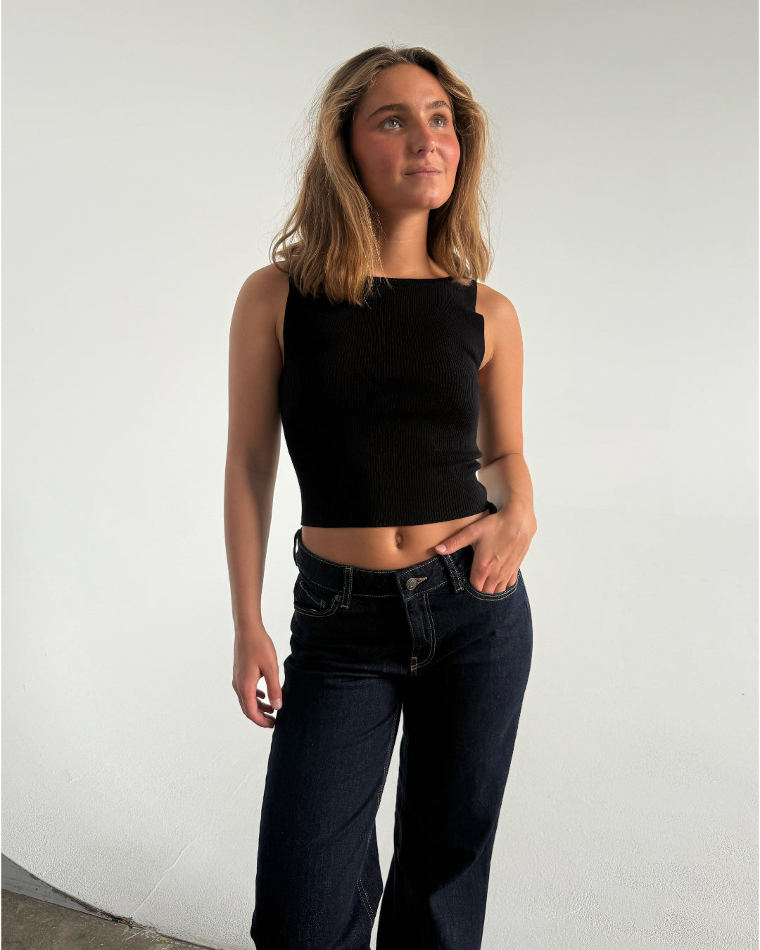Modelfoto af pige som bærer en Posie top i sort, samt et par mørkeblå jeans. Alt fra By Sofie Sønderby