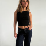 Modelfoto af pige som bærer en Posie top i sort, samt et par mørkeblå jeans. Alt fra By Sofie Sønderby