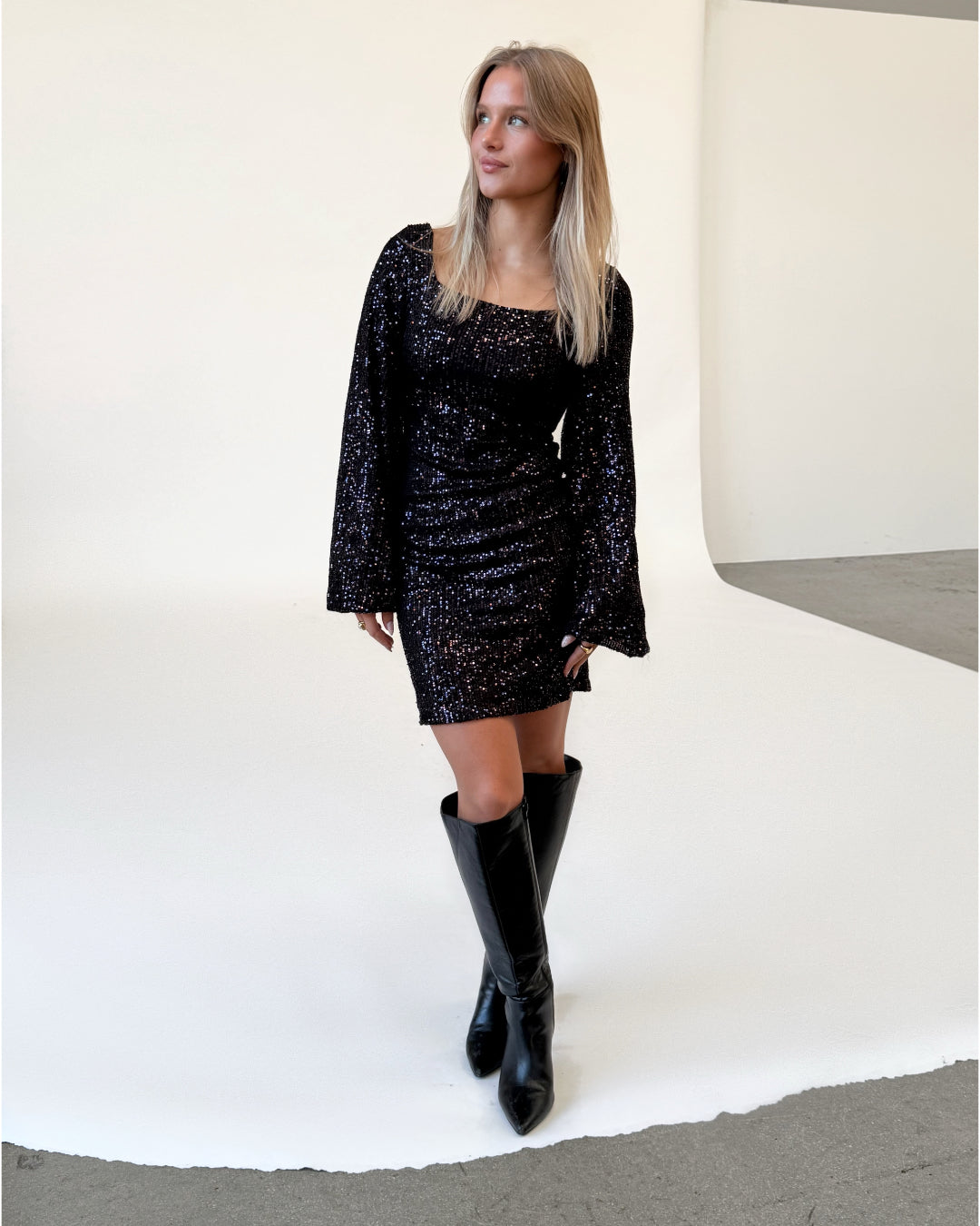 Modelfoto af pige i lilla RAYA kjole med pailetter, samt sorte støvler. Alt er fra BySofieSønderby.