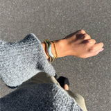 Modelfoto af en Robin guld armbånd. Baggrund er grå. Fra BySofieSønderby