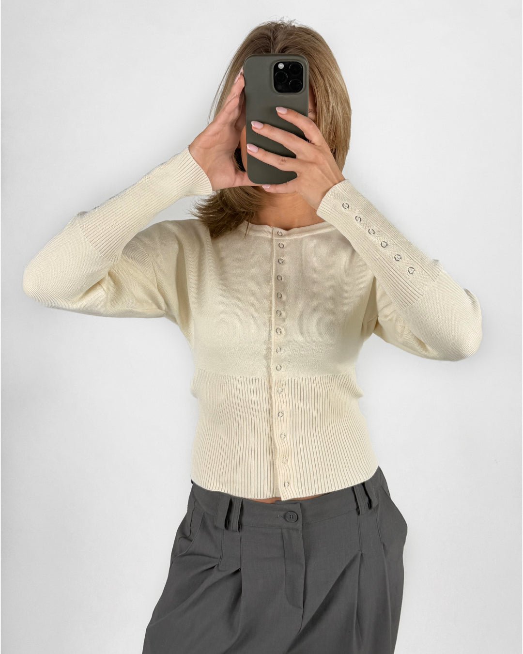 Modelfoto af pige i cremefarvet RORY striktrøje med knapper, samt grå LISA bukser. Alt er fra BySofieSønderby.