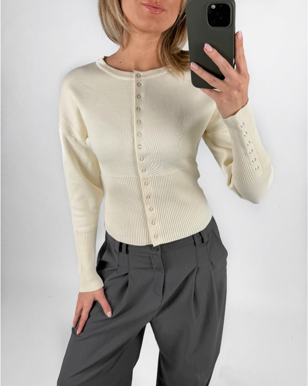 Modelfoto af pige i cremefarvet RORY striktrøje med knapper, samt grå LISA bukser. Alt er fra BySofieSønderby.