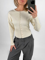 Modelfoto af pige i cremefarvet RORY striktrøje med knapper, samt grå LISA bukser. Alt er fra BySofieSønderby.