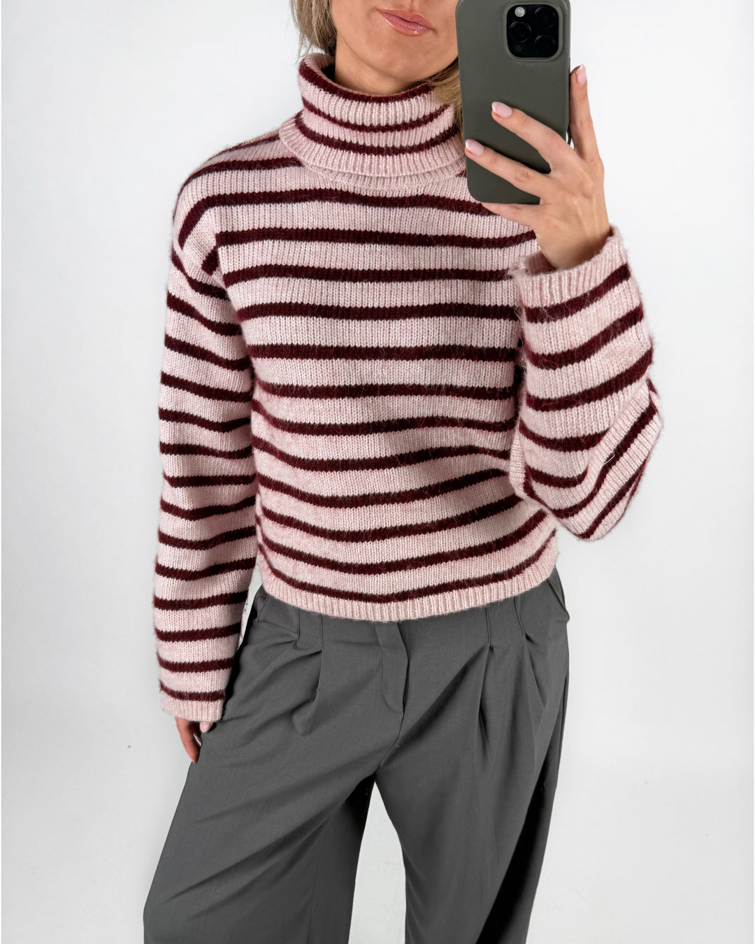 Modelfoto af pige i lyserødstribet ROSANNA striktrøje med rullekrave, samt grå LISA bukser. Alt er fra BySofieSønderby.