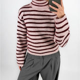 Modelfoto af pige i lyserødstribet ROSANNA striktrøje med rullekrave, samt grå LISA bukser. Alt er fra BySofieSønderby.