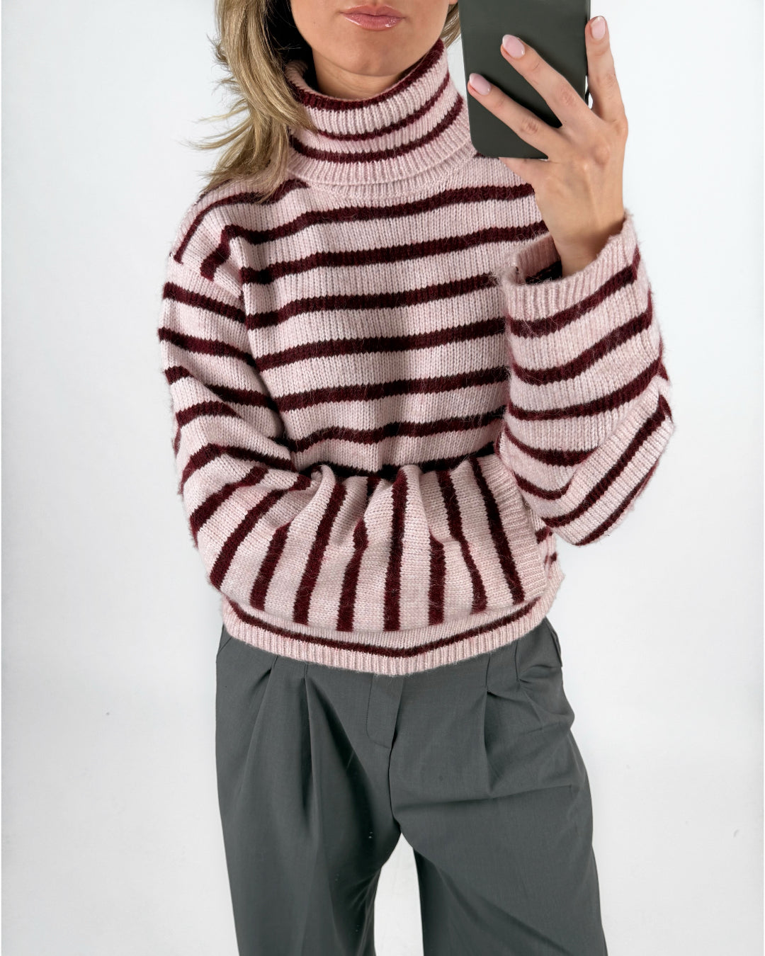 Modelfoto af pige i lyserødstribet ROSANNA striktrøje med rullekrave, samt grå LISA bukser. Alt er fra BySofieSønderby.