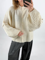 Modelfoto af pige med creme farvet RUTHIE strik cardigan, samt grå MILAN bukser. Set forfra. Alt er fra BySofieSønderby