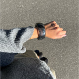 Modelfoto af en Saige armbånd i grå. Baggrund er grå. Fra BySofieSønderby
