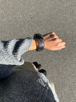 Modelfoto af en Saige armbånd i grå. Baggrund er grå. Fra BySofieSønderby