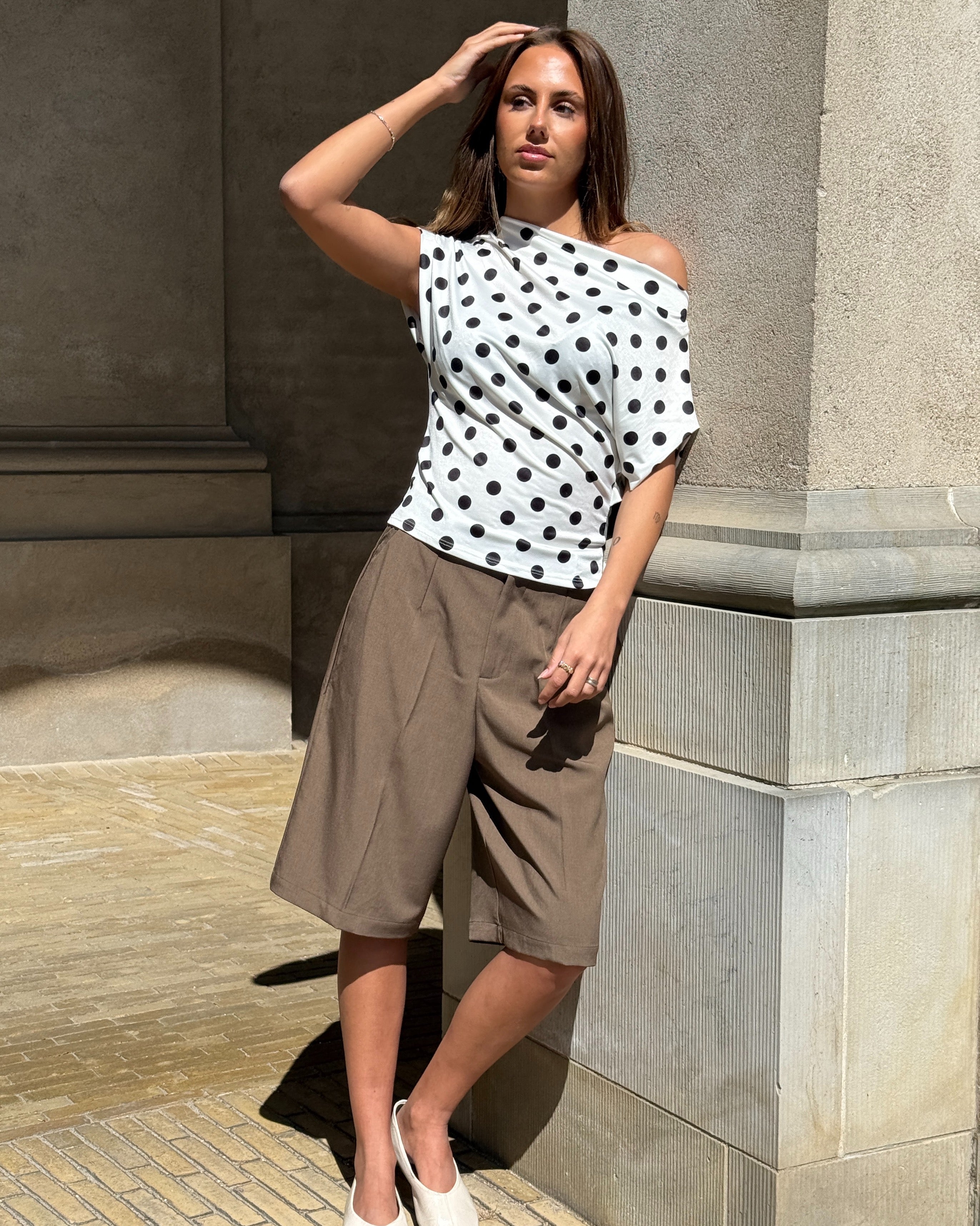 Modelbillede af SAMIRA one shoulder top, hvid og HARLEE shorts, brun. Fra BySofieSønderby