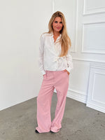 Modelfoto af pige i lyserøde SELENA bukser, samt hvid HOPE top. Alt er fra BySofieSønderby.