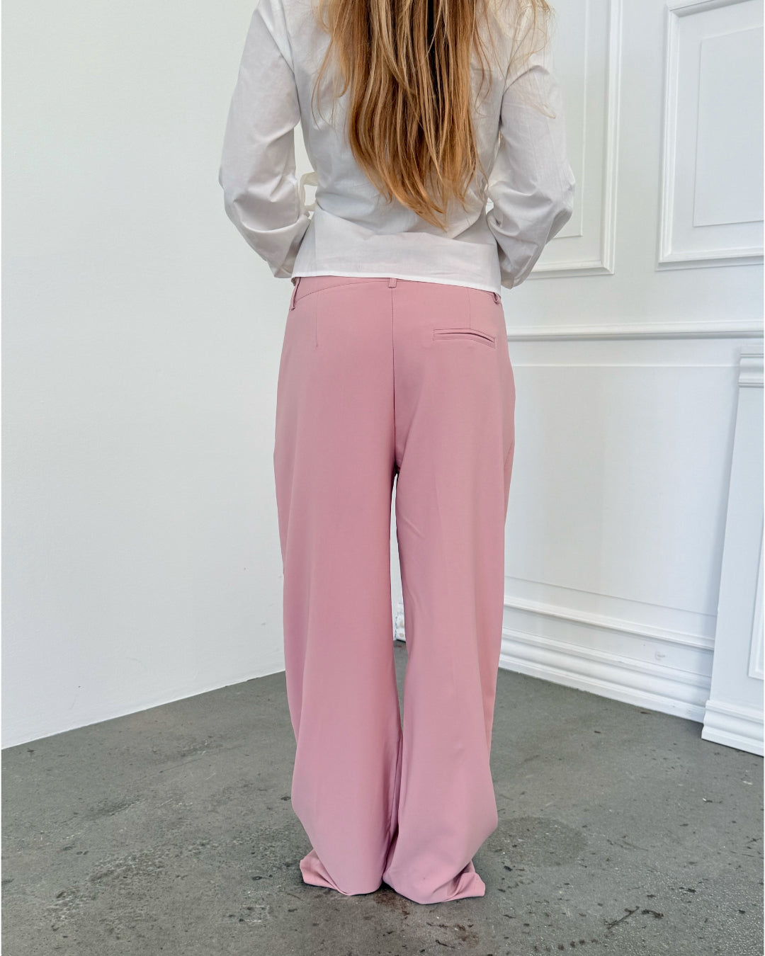 Modelfoto af pige i lyserøde SELENA bukser, samt hvid HOPE top. Alt er fra BySofieSønderby.