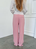 Modelfoto af pige i lyserøde SELENA bukser, samt hvid HOPE top. Alt er fra BySofieSønderby.