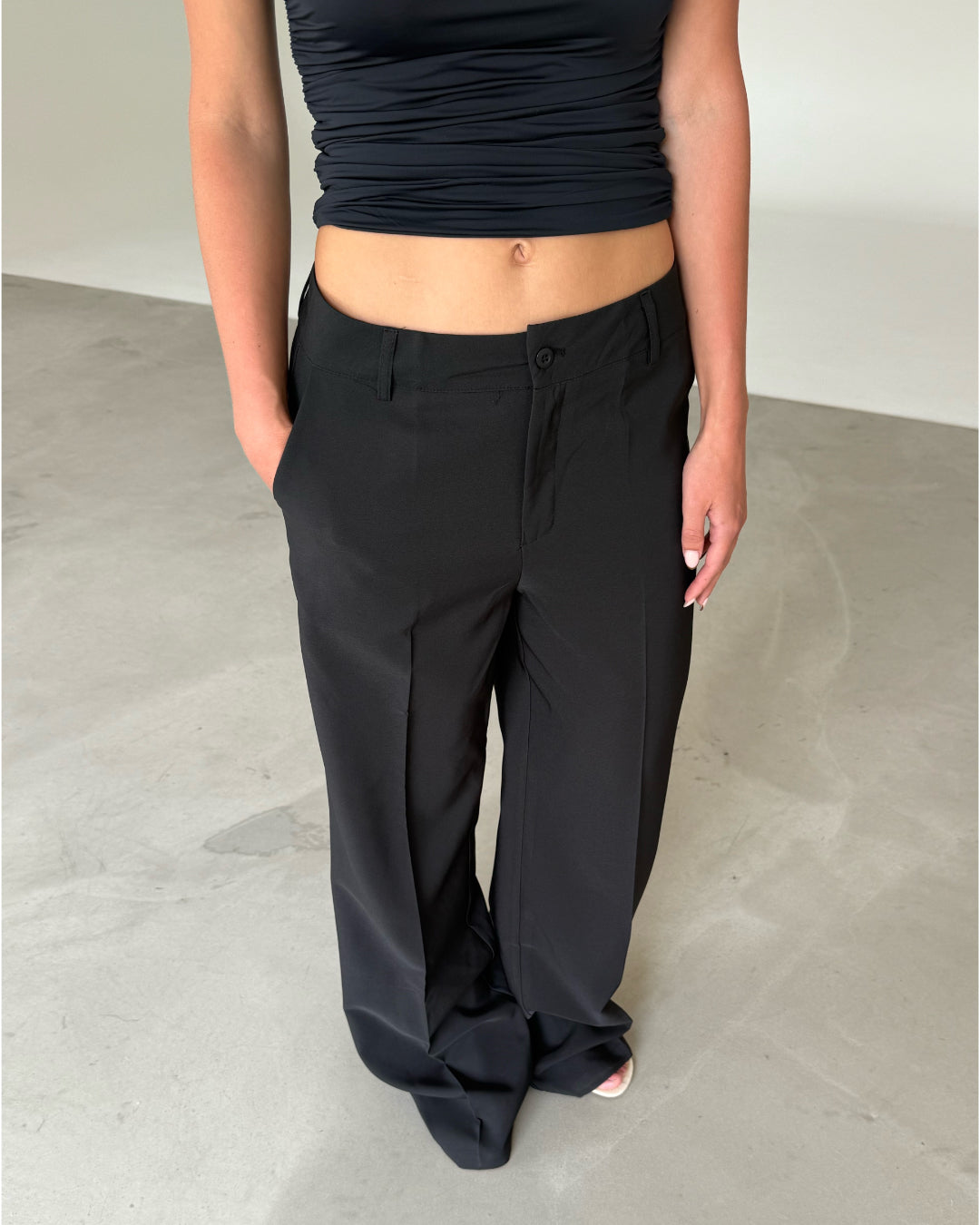 Modelfoto af pige som bærer sorte SELENA bukser og en sort top. Alt er fra BySofieSønderby