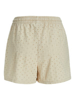 Beige shorts med elastisk talje har et blomstret perforeret mønster. De er alene i et neutralt, hvidt fotostudie uden andre genstande.