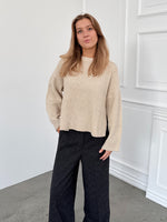 Modelfoto af pige i creme SIGGA strik, samt sortmelerede ELLIS bukser. Alt er fra BySofieSønderby.