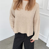 Modelfoto af pige i creme SIGGA strik, samt sortmelerede ELLIS bukser. Alt er fra BySofieSønderby.