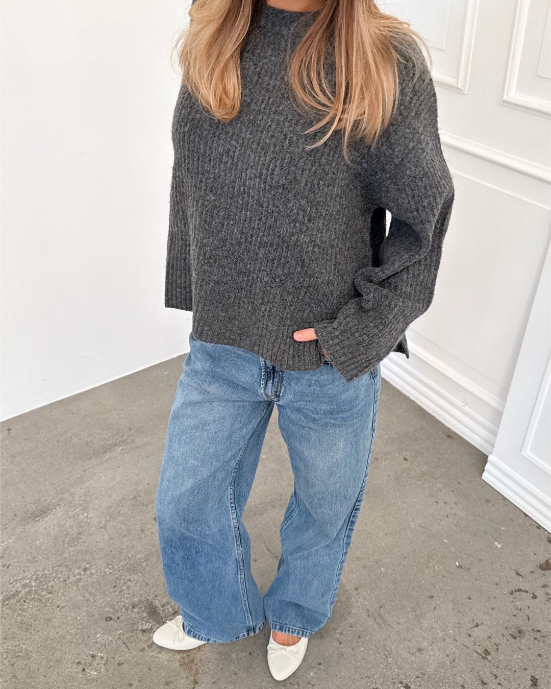 Modelfoto af pige i grå SIGGA strik, samt blå NANNA jeans. Alt er fra BySofieSønderby.