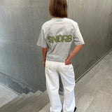 Stemningsbillede af pige der bærer en grå t-shirt med army SNDRB tryk og hvide NANNA jeans.  Fra BySofieSønderby