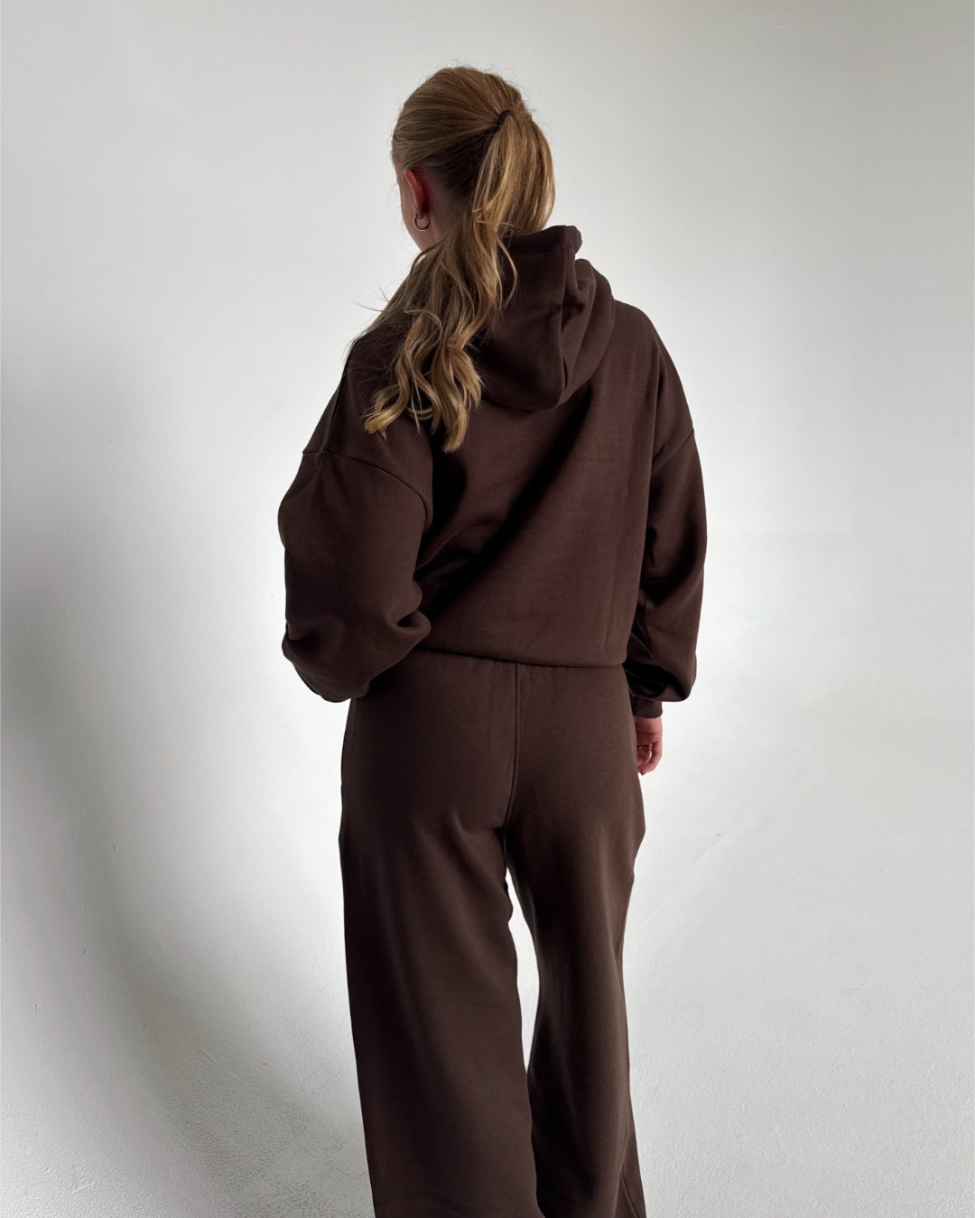 Modelfoto af pige som bærer en Studio Vesterbro hoodie i brun, samt Studio Vesterbro bukser i brun. Alt fra By Sofie Sønderby
