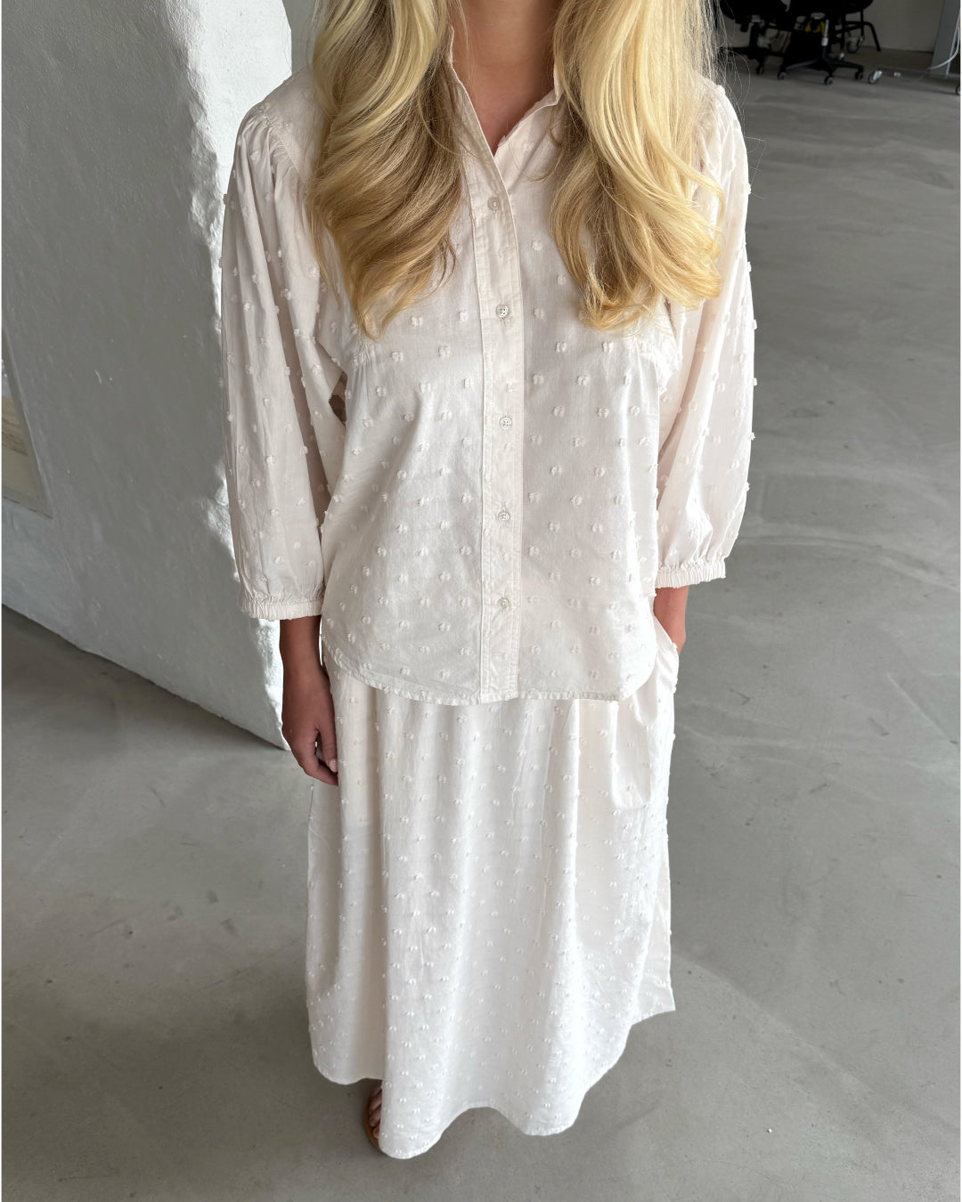 Modelfoto af pige som bærer cremefarvet SUNELA skjorte, samt tilhørende SUNELA nederdel. Alt er fra BySofieSønderby