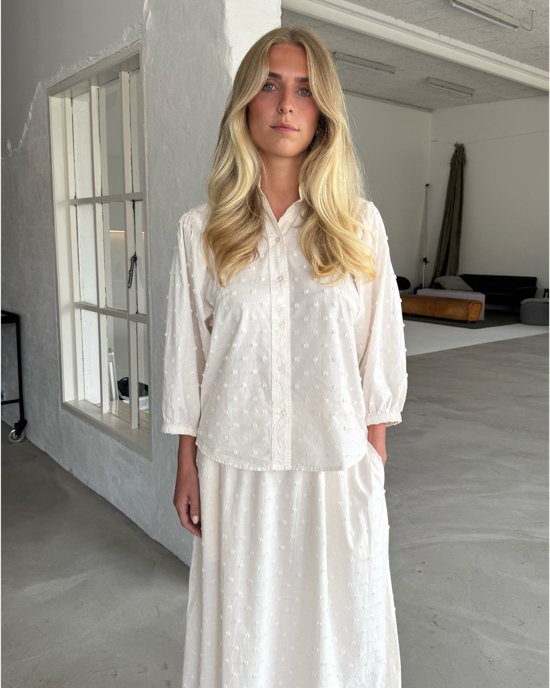 Modelfoto af pige som bærer cremefarvet SUNELA skjorte, samt tilhørende SUNELA nederdel. Alt er fra BySofieSønderby