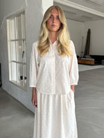 Modelfoto af pige som bærer cremefarvet SUNELA skjorte, samt tilhørende SUNELA nederdel. Alt er fra BySofieSønderby
