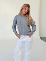 Modelfoto af pige i grå THESS  strik hoodie, samt hvide NANNA jeans. Alt er fra BySofieSønderby.