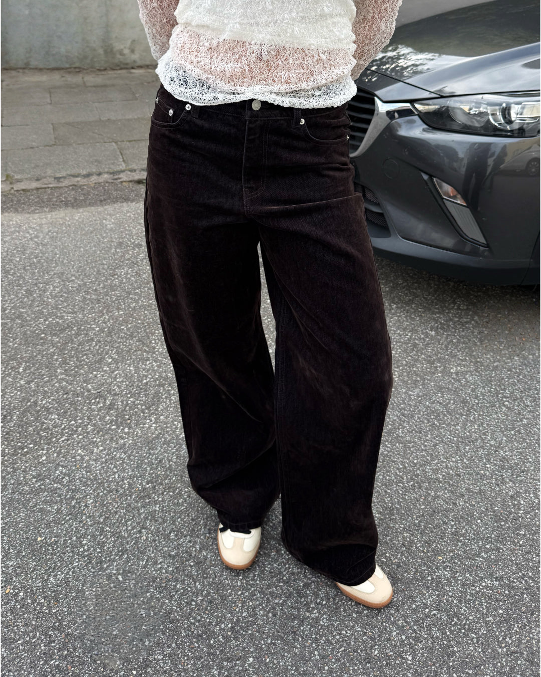 Modelfoto af pige i brune Tokyo bukser og en hvid blonde top. Alt er fra BySofieSønderby