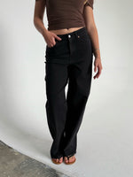 Modelfoto af pige som bærer et par sorte Tokyo jeans, samt iført en brun Thora top og sorte Carmen sandaler. Alt fra By Sofie Sønderby