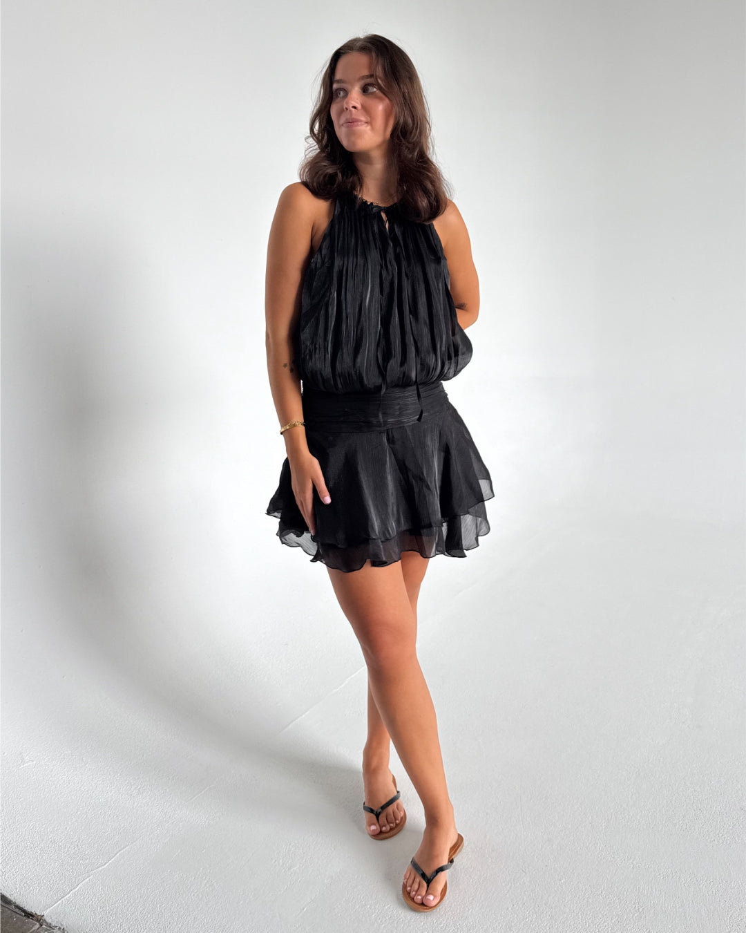Modelfoto af pige som bærer en sort Vera kjole, samt Carmen sandaler. Hvid baggrund. Alt fra By Sofie Sønderby