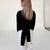 Modelfoto af pige i sort WHITNEY strik, samt hvide NANNA jeans. Alt er fra BySofieSønderby.