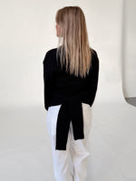 Modelfoto af pige i sort WHITNEY strik, samt hvide NANNA jeans. Alt er fra BySofieSønderby.