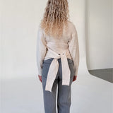 Modelfoto af pige i beige WHITNEY strik, samt grå NANNA jeans. Alt er fra BySofieSønderby.