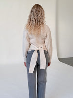 Modelfoto af pige i beige WHITNEY strik, samt grå NANNA jeans. Alt er fra BySofieSønderby.